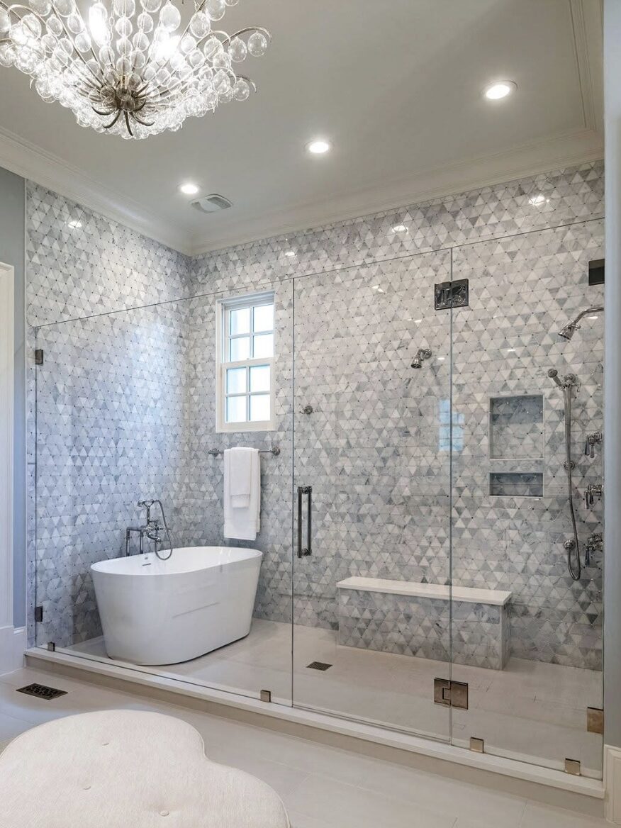 Luxury bathroom remodel with freestanding tub, glass shower enclosure, patterned tile wall, and chandelier