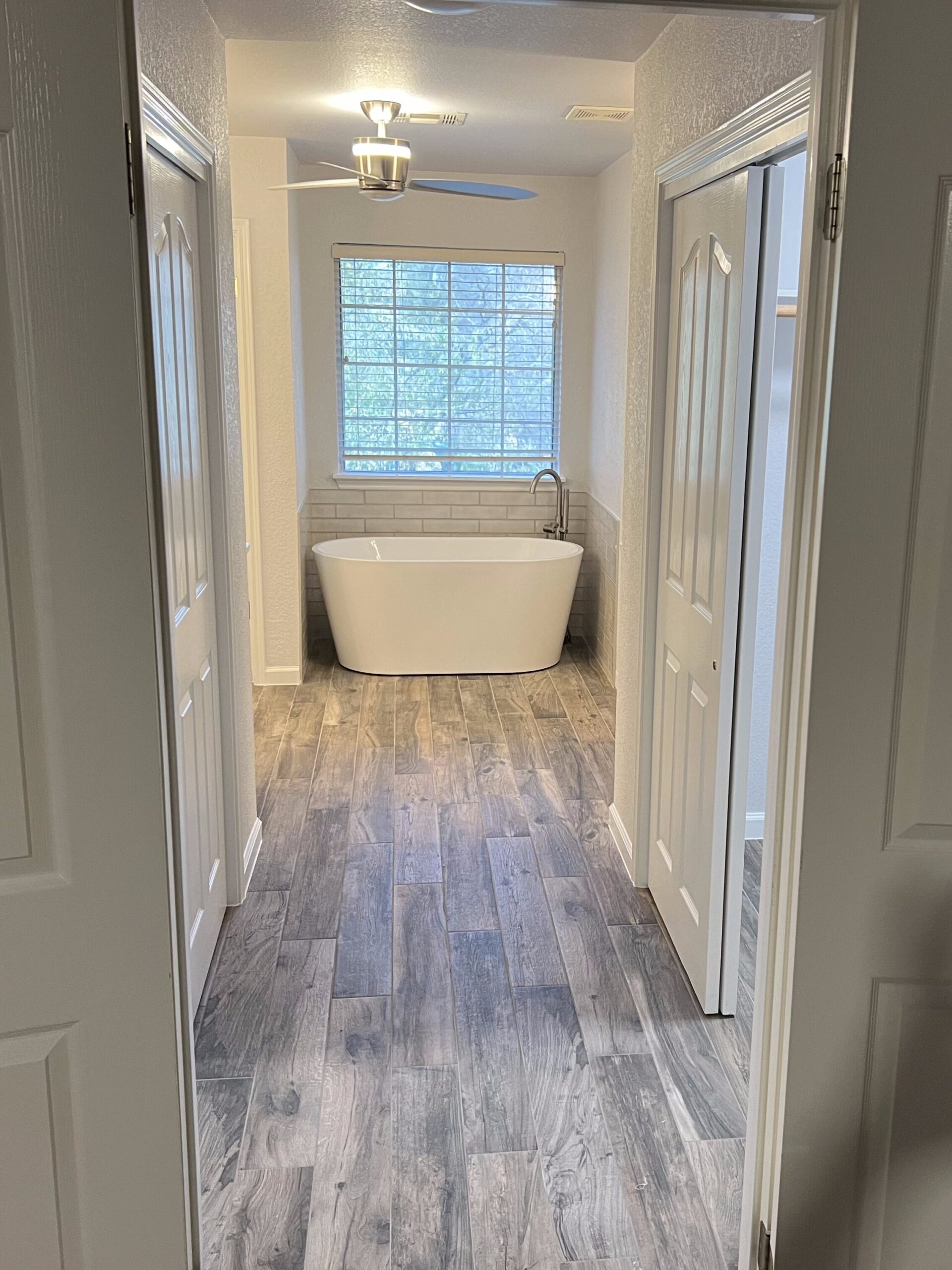 Buda master bathroom remodel with freestanding tub, tile flooring, trim work, and updated bathroom finishes