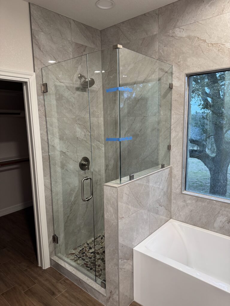 Driftwood master bathroom remodel with glass shower enclosure, tile walls, bathtub, and updated bathroom finishes