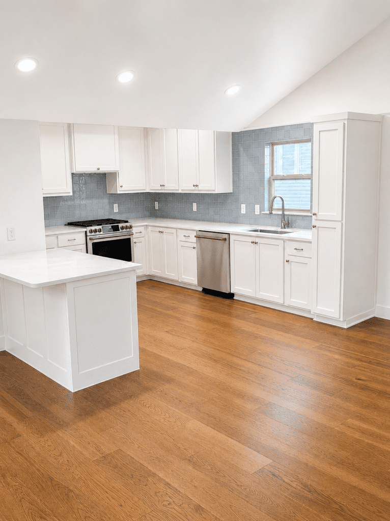 Bouldin Austin whole house remodel after photo with white kitchen cabinets, blue tile backsplash, hardwood flooring, updated layout, and interior finish work