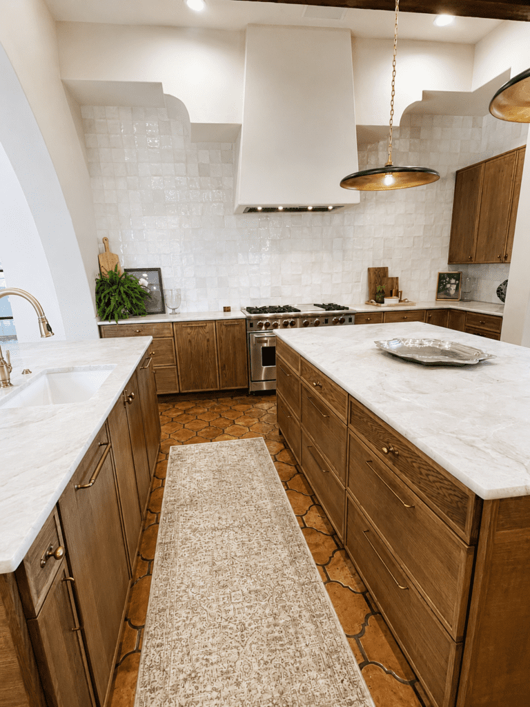Bee Cave Spanish Oaks kitchen remodel with wood cabinets, white countertops, handmade tile backsplash, large kitchen island, Saltillo-style flooring, and brass fixtures